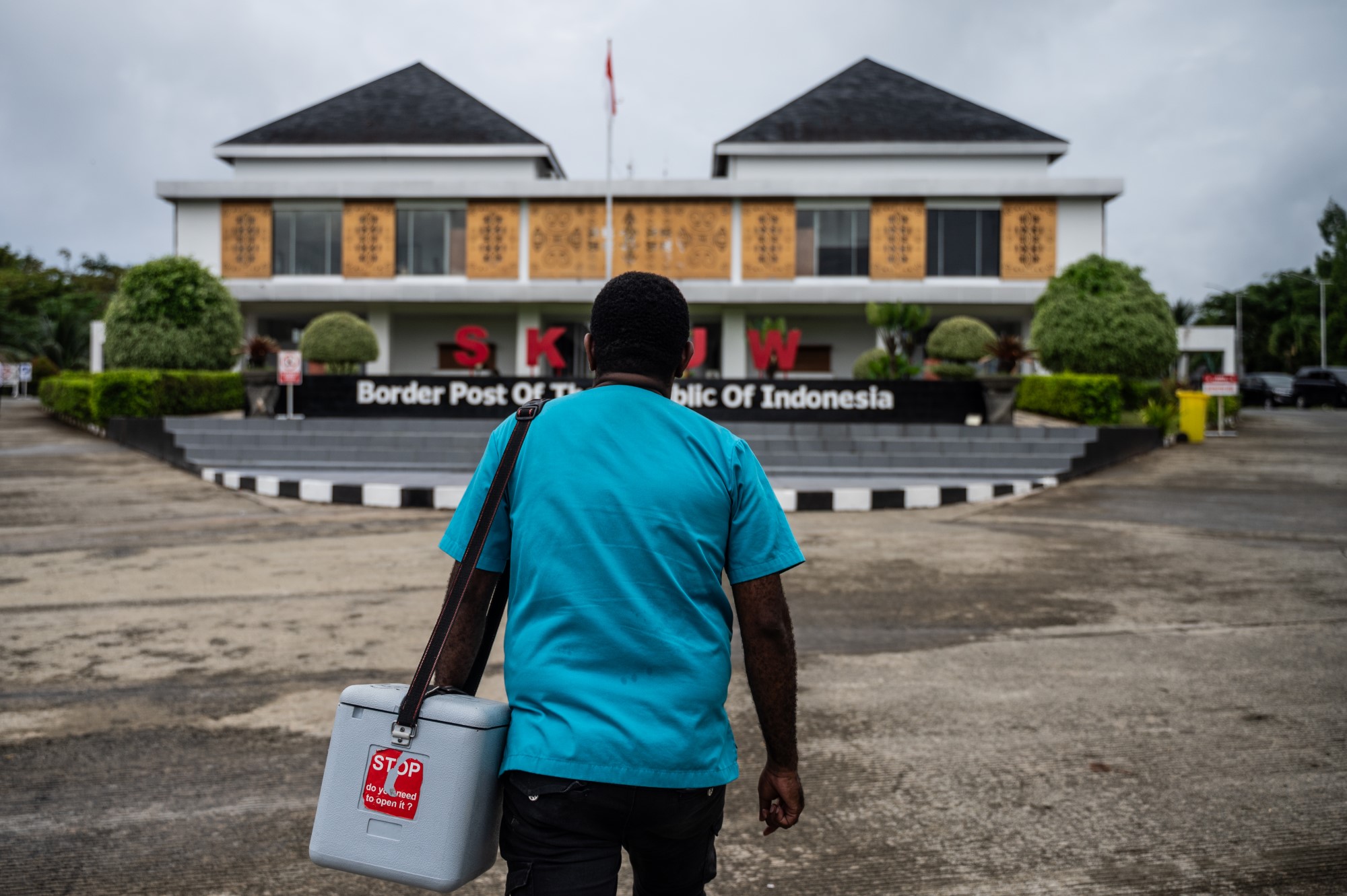 A person carrying a vaccine carrier box walking towards the Cross-Border Post Skouw of Indonesia-Papua New Guinea