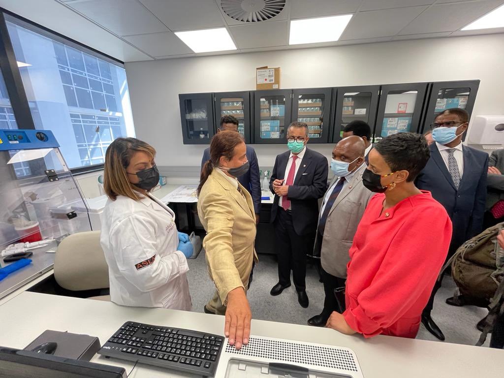 Several people in masks watching a demonstration in a lab
