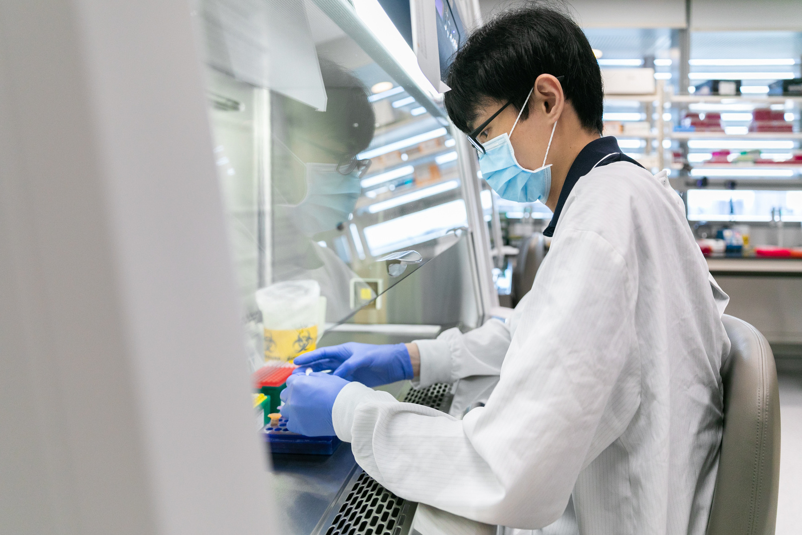 A lab worker in a mask and lab coat