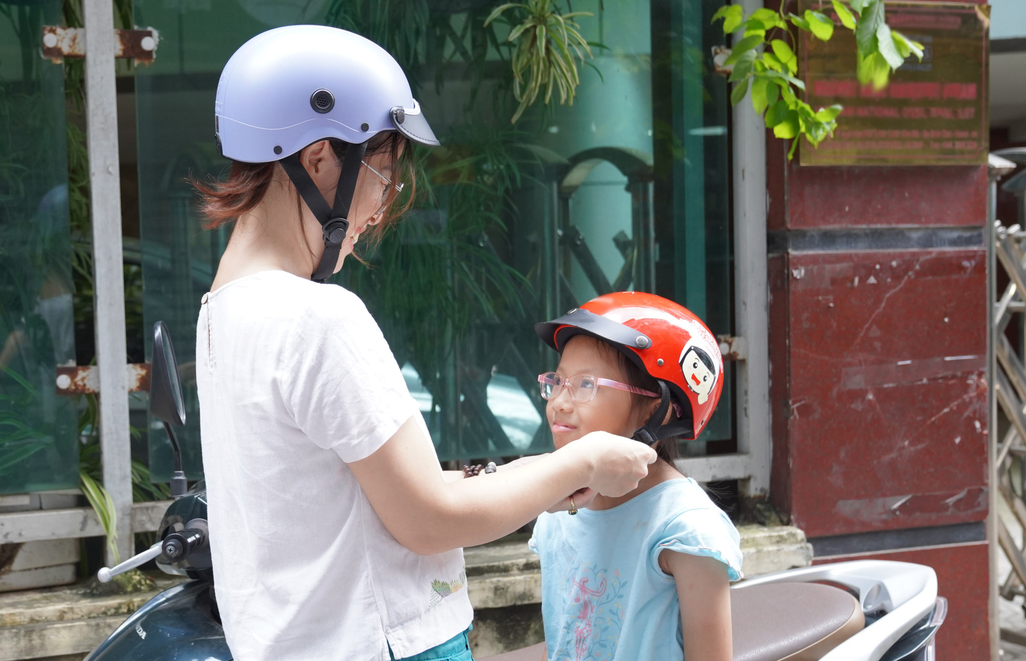 Mother helps her child wear the helmet